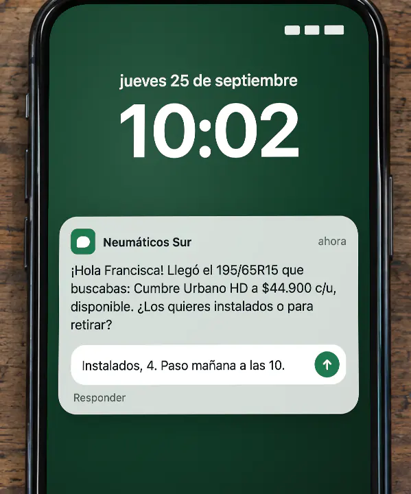 Un teléfono sobre el mesón del taller muestra en la pantalla bloqueada un aviso de Neumáticos Sur: «¡Hola Francisca! Llegó el 195/65R15 que buscabas: Cumbre Urbano HD a $44.900 c/u, disponible. ¿Los quieres instalados o para retirar?». Desde la misma notificación, la clienta responde: «Instalados, 4. Paso mañana a las 10.»